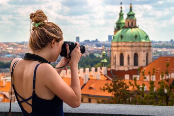 a woman taking a photo of a castle in Czech Republic