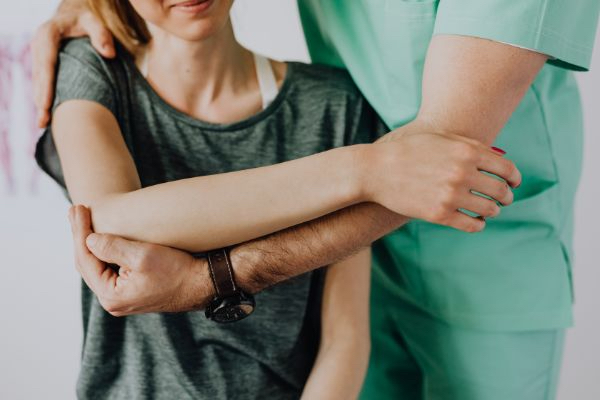 orthopedist stretching shoulder of female patient