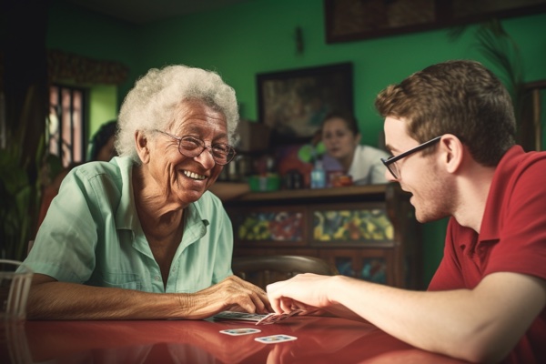 Elderly woman in carehome plays cards with a young volunteer, fostering connections across generations.