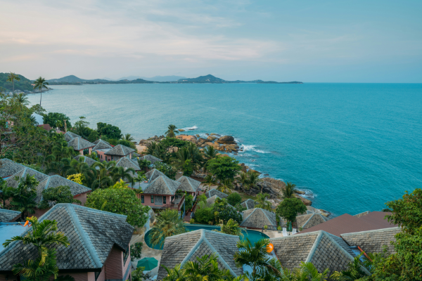 Thailand A view of a tropical hillside coastal village in Thailand alongside the clear blue waters of the ocean
