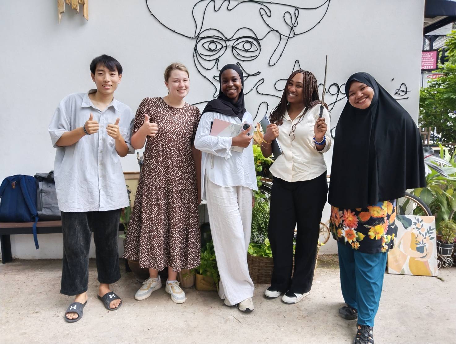 Group of five diverse friends smiling and posing happily outside a cafe
