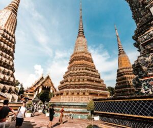 Tourists walking among ornate temple spires at Wat Pho in Bangkok