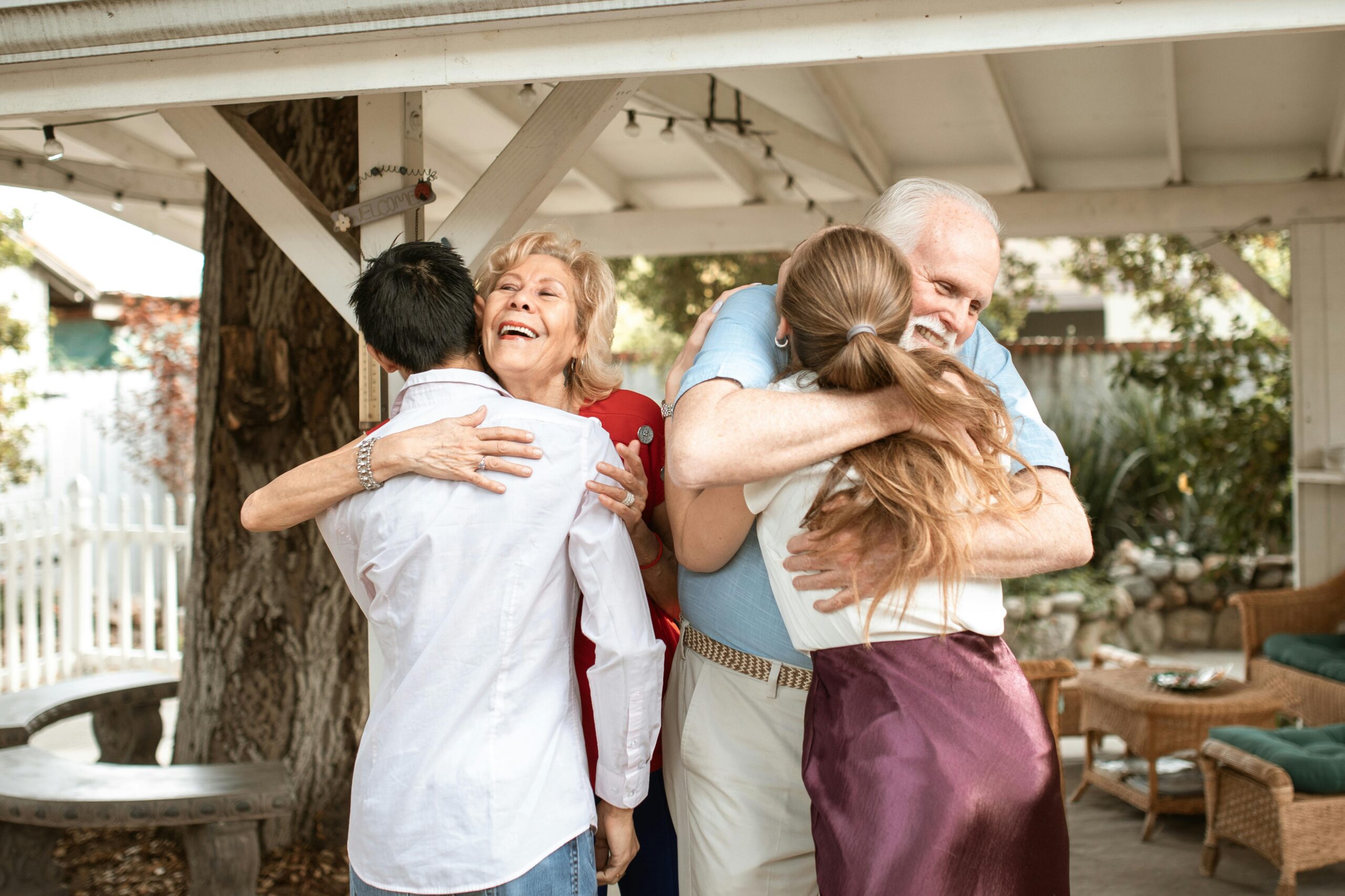 Two older adults warmly hug younger family members in a joyful reunion