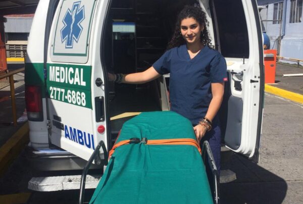 Person standing in front of an ambulance in Costa Rica with a hand on a gurney