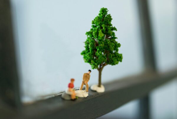 two small people figurines next to tree figurine