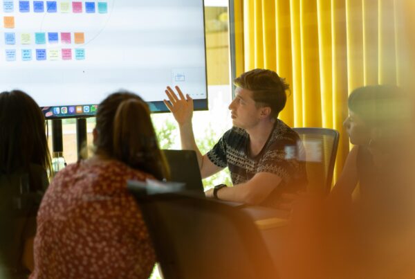 man sitting at table gesturing to screen