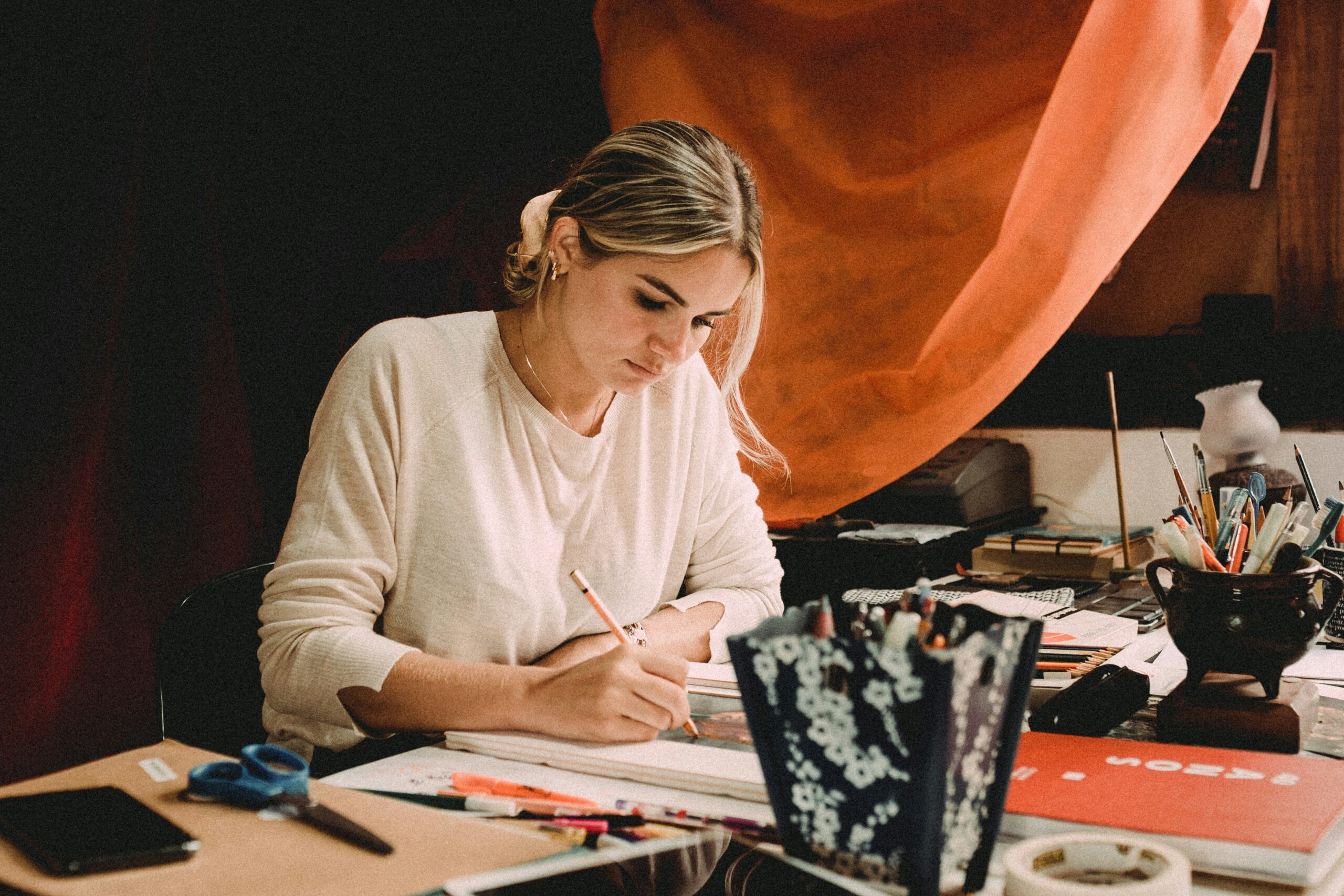 Two people working at a desk with art on the wall