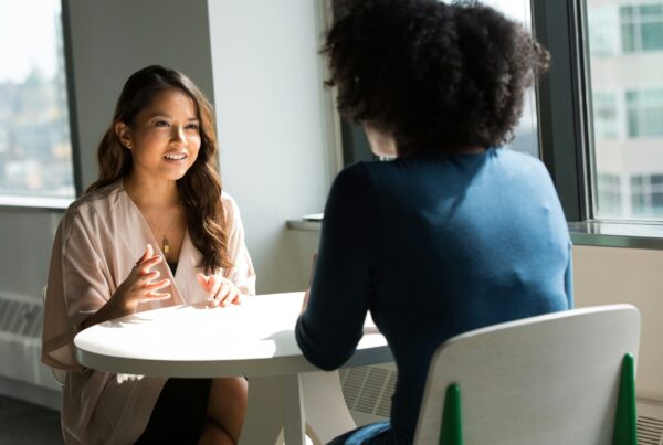 two women sitting at a table and speing