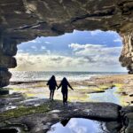 Two women walking through a cave in Ireland.