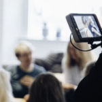 A woman using a video camera to record a conversation.