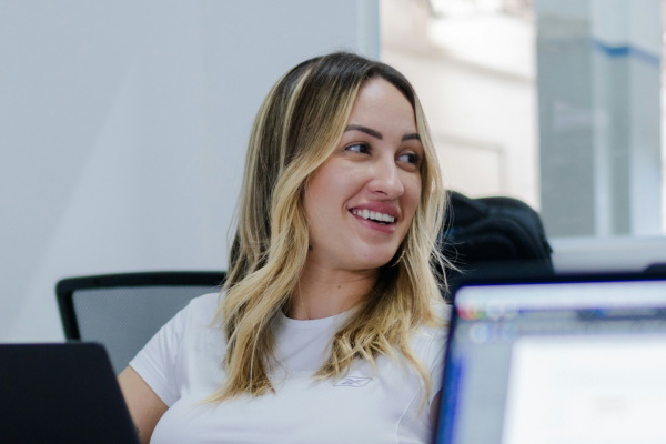 A woman smiling while working on a laptop.