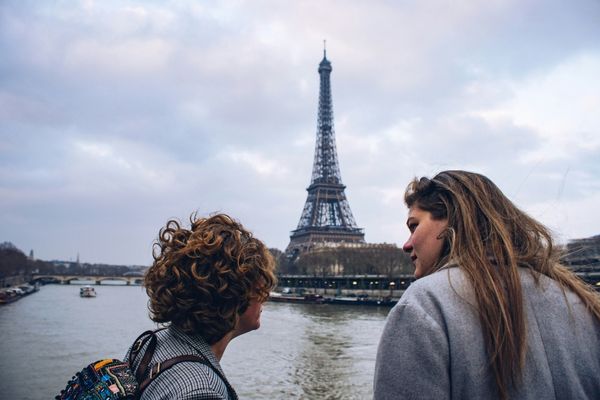 Two people talking near the Eiffel Tower in Paris, France.